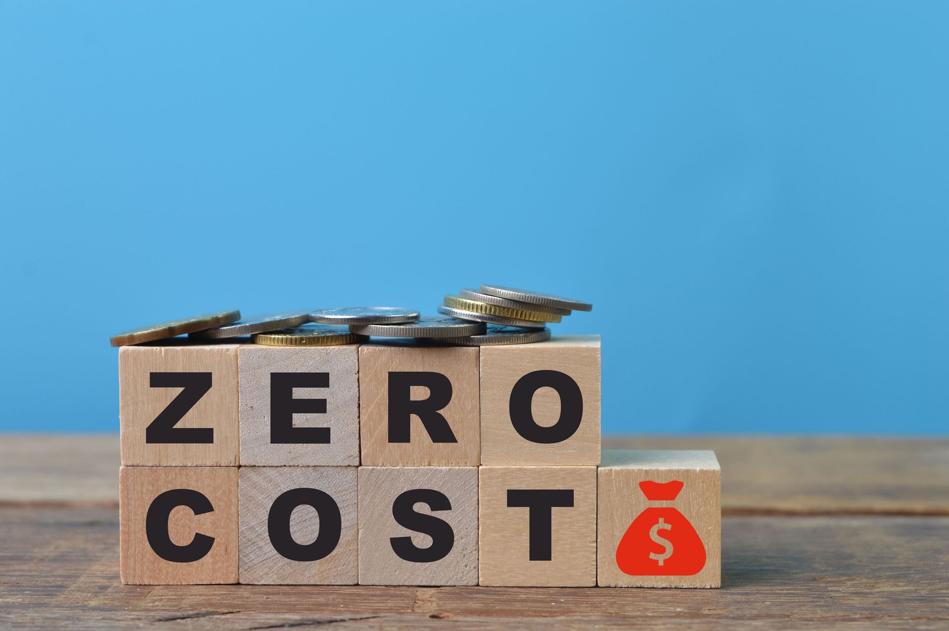 Coins, money symbol and wooden blocks with text ZERO COST